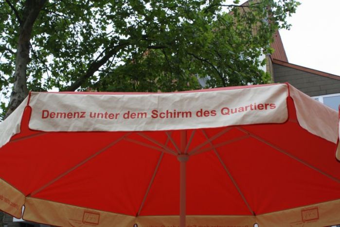 Foto des roten Schirms mit der Aufschrift "Demenz unter dem Schirm des Quartiers"