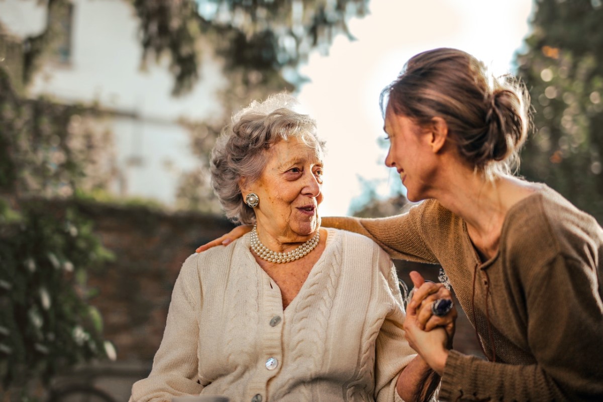 Eine Seniorin und ihre Angehörige lächeln sich an.