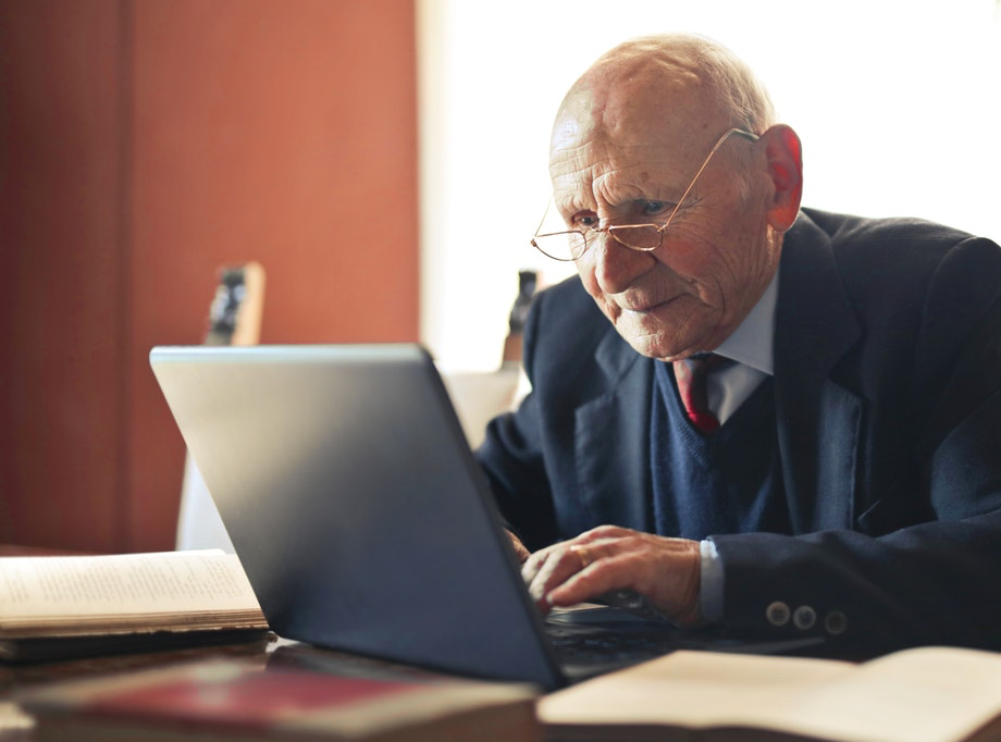 Ein Senior arbeitet an einem Laptop.