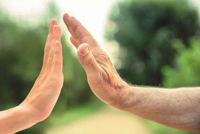 Alte und junge Hand schlagen einander ab. Ähnlich dem gib mir fünf.