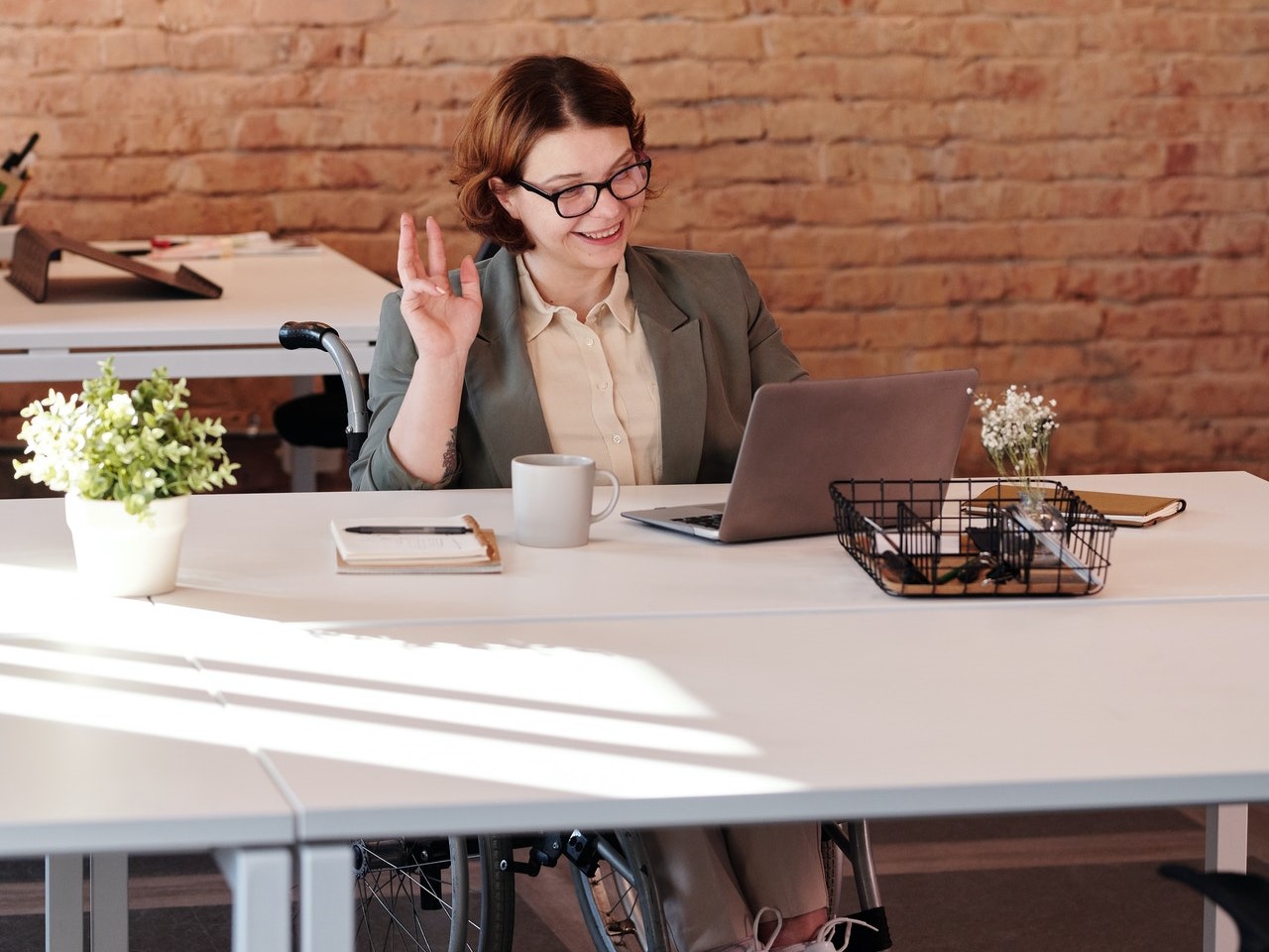 Eine Frau, die in einem Rollstuhl sitzt, nimmt über ihren Laptop an einem Meeting teil.