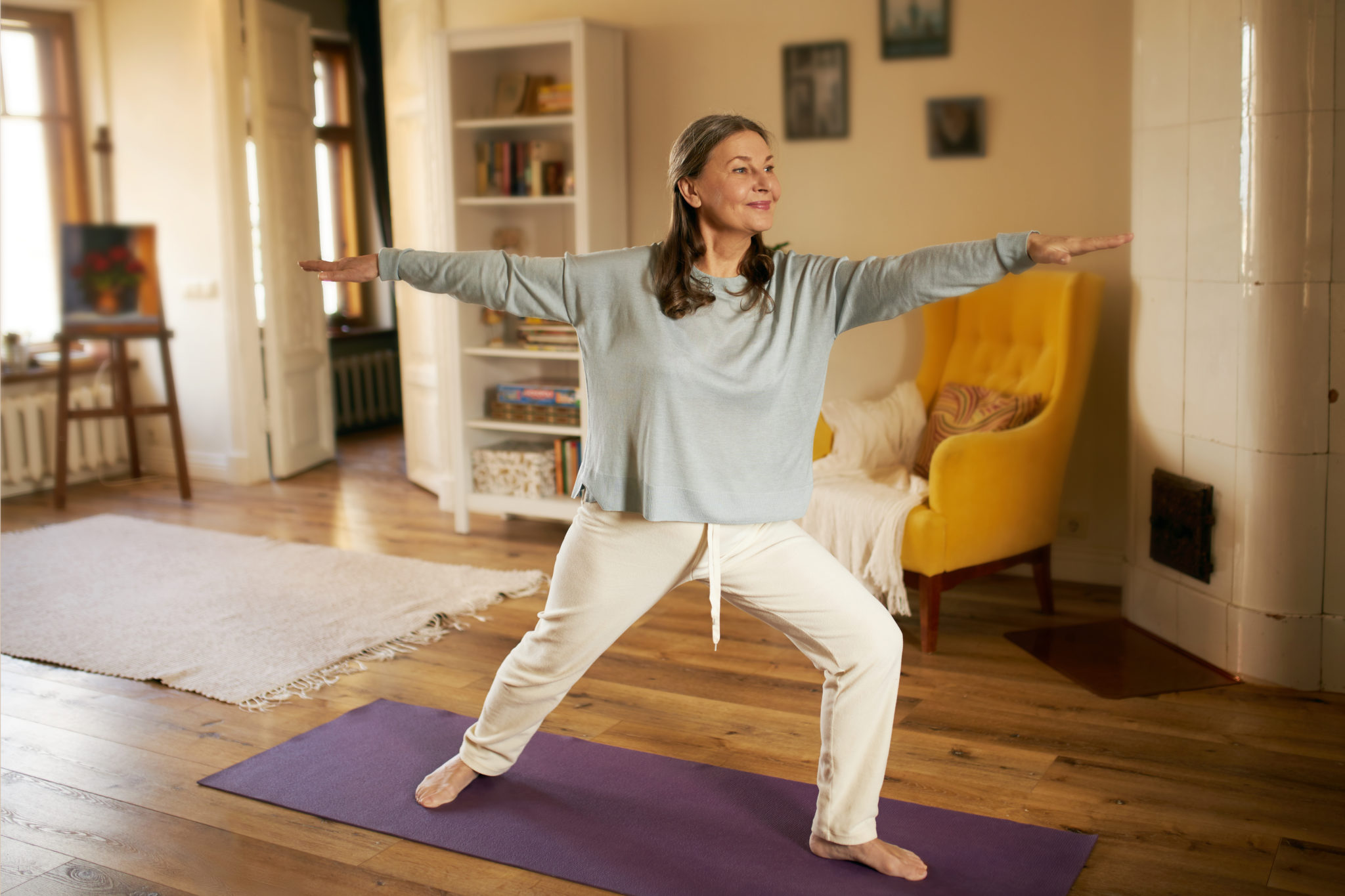 Eine Frau mach Yoga. Sie stellt ein Bein nach vorne und streckt einen Arm nach hinten und einen nach vorne.