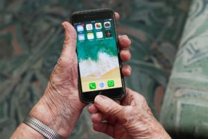 Hände einer älteren Person halten Smartphone