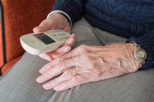 Hände einer älteren Person halten ein schnurloses Festnetztelefon