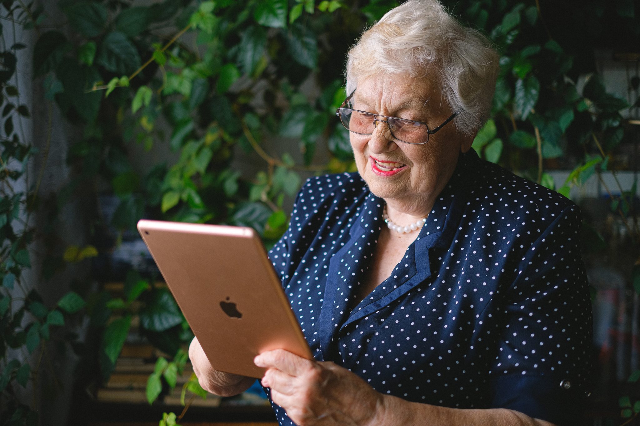 Ältere Dame hält ein iPad und lächelt