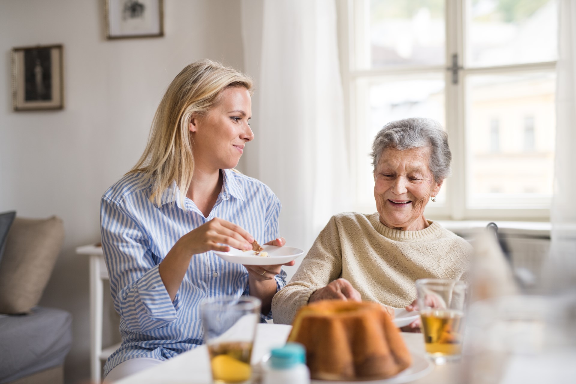 Eine Frau isst gemeinsam mit ihrer pflegebedürftigen Mutter Kuchen.