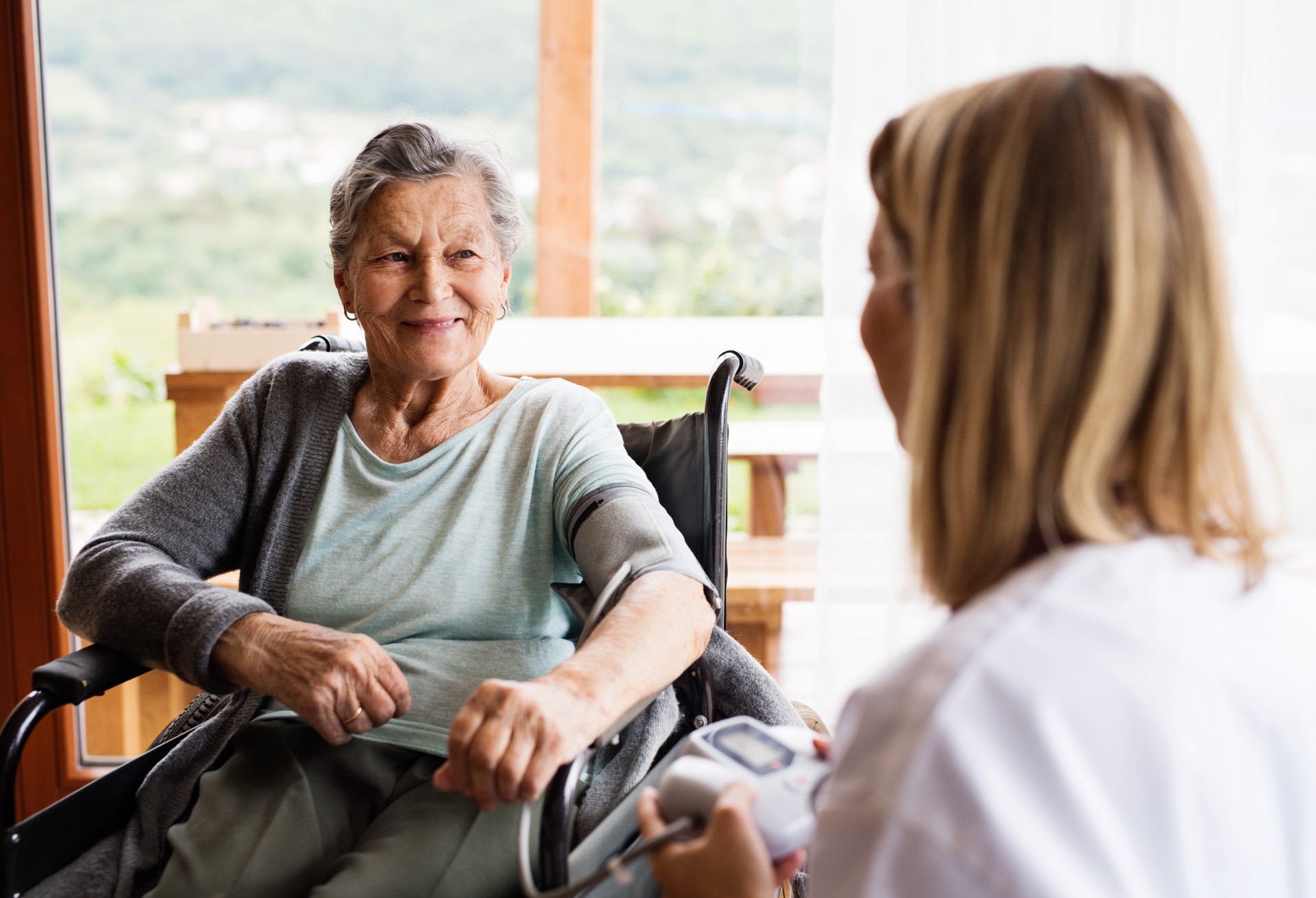 Einer Seniorin in einem sitzen in einem Rollstuhl in lächelt ihr Gegenüber an.