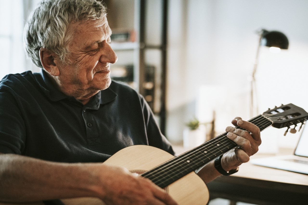 Ein Senior spielt Gitarre.