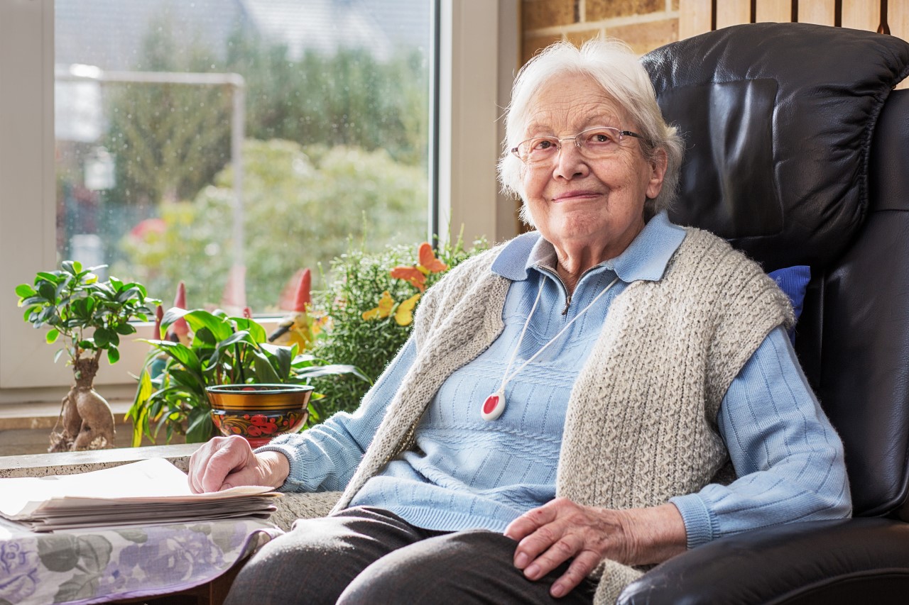 Eine Seniorin sitzt zuhause in ihrem Sessel.