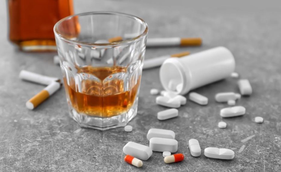Glas mit Alkohol, Zigaretten und Tabletten