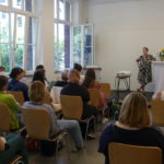 Blick über das Plenum auf die Bühne, wo gerade die Podiumsdiskussion stattfindet