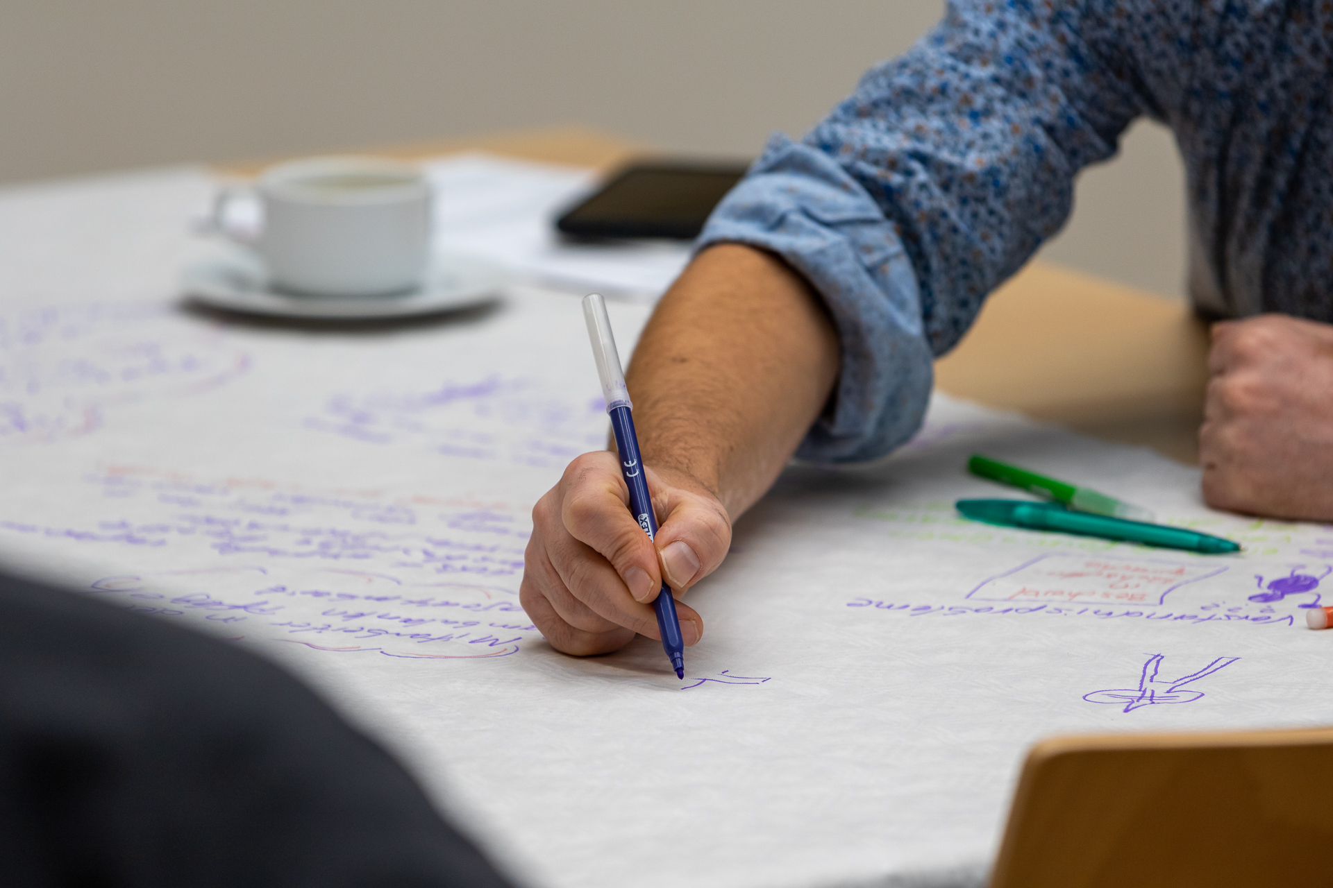 Beim Wold Café schreibt ein Teilnehmender seine Ideen auf ein großes Papier