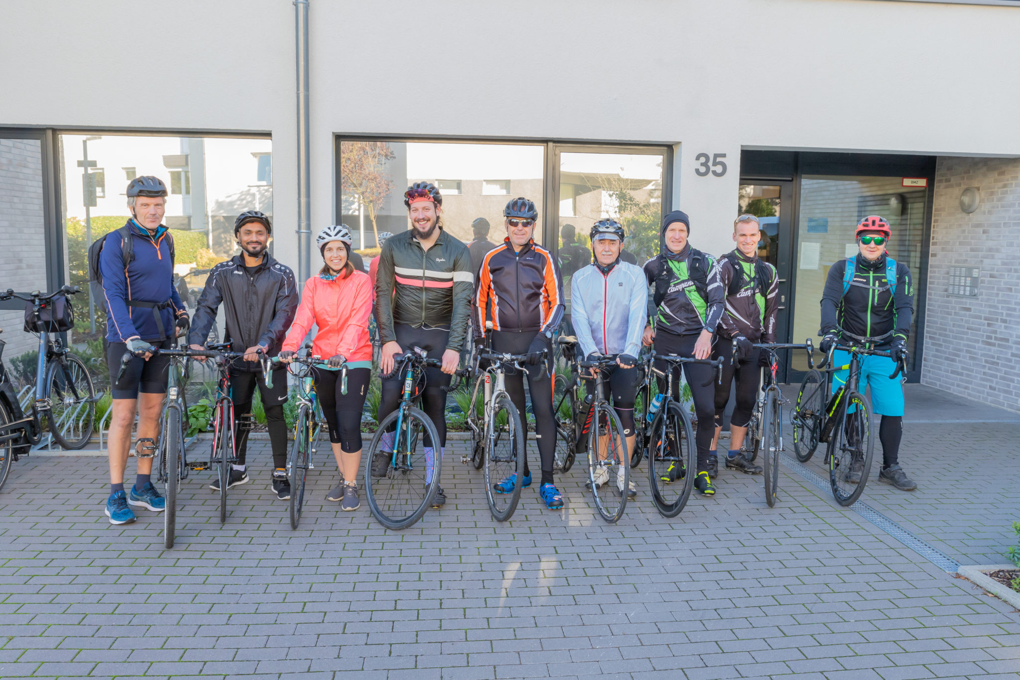 Neu Personen in Fahrradkleidung mit Fahrrad in der Reihe aufgestellt.