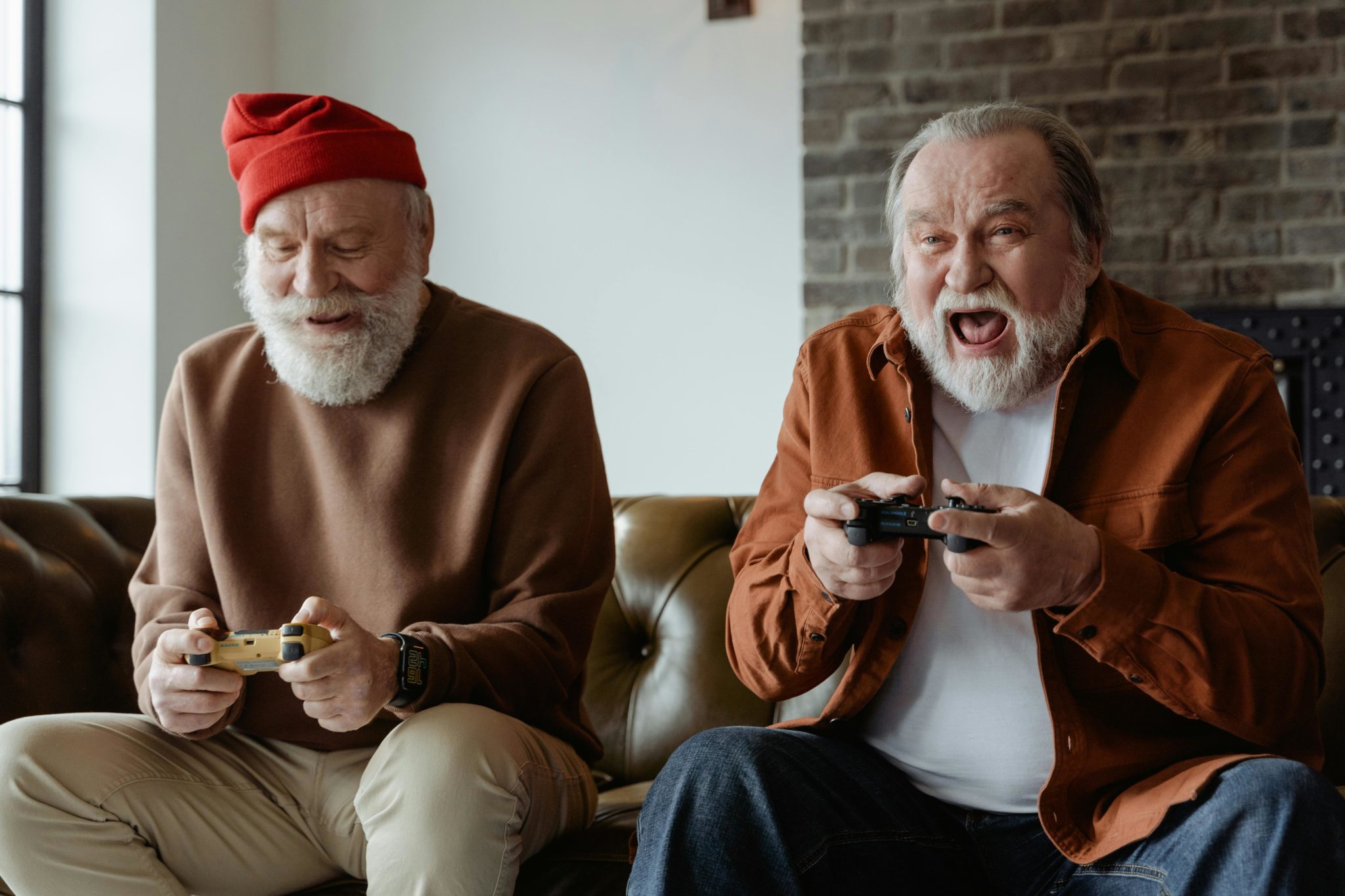 2 ältere Männer sitzen auf der Couch und spielen mit der Konsole