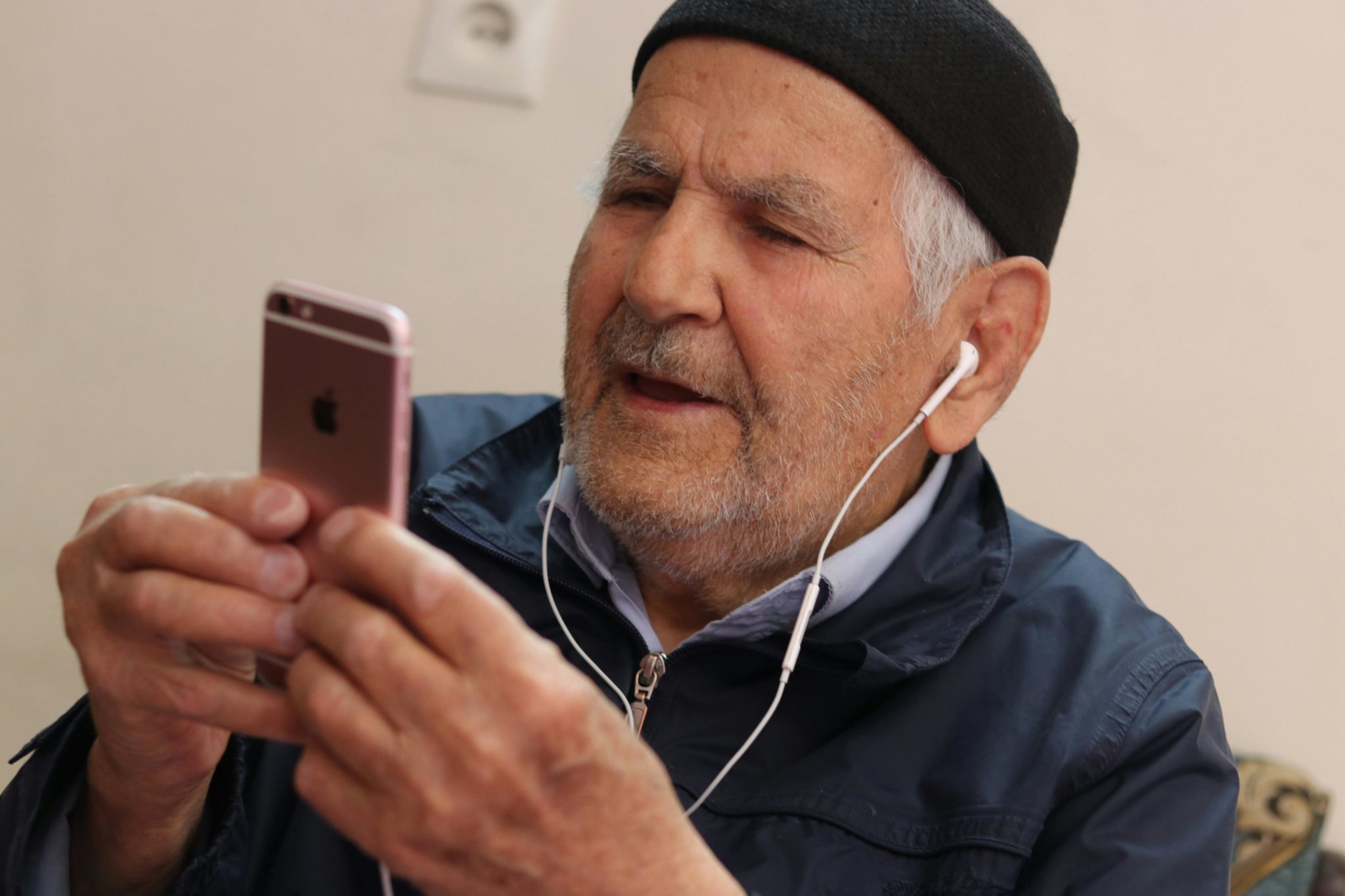 Eine ältere Person schaut auf sein Mobilfunkgerät.