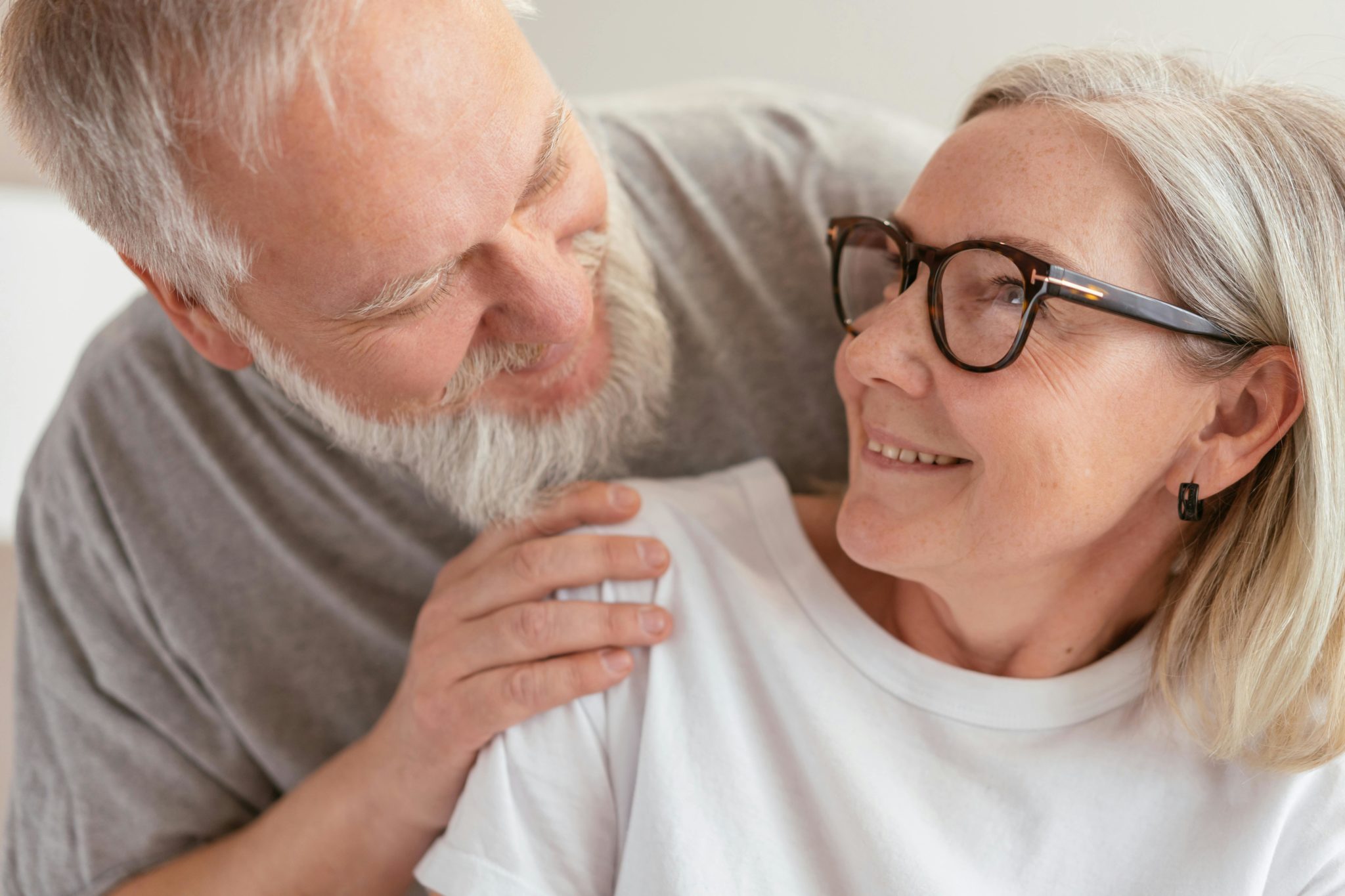 Mann umarmt Seniorin von hinten