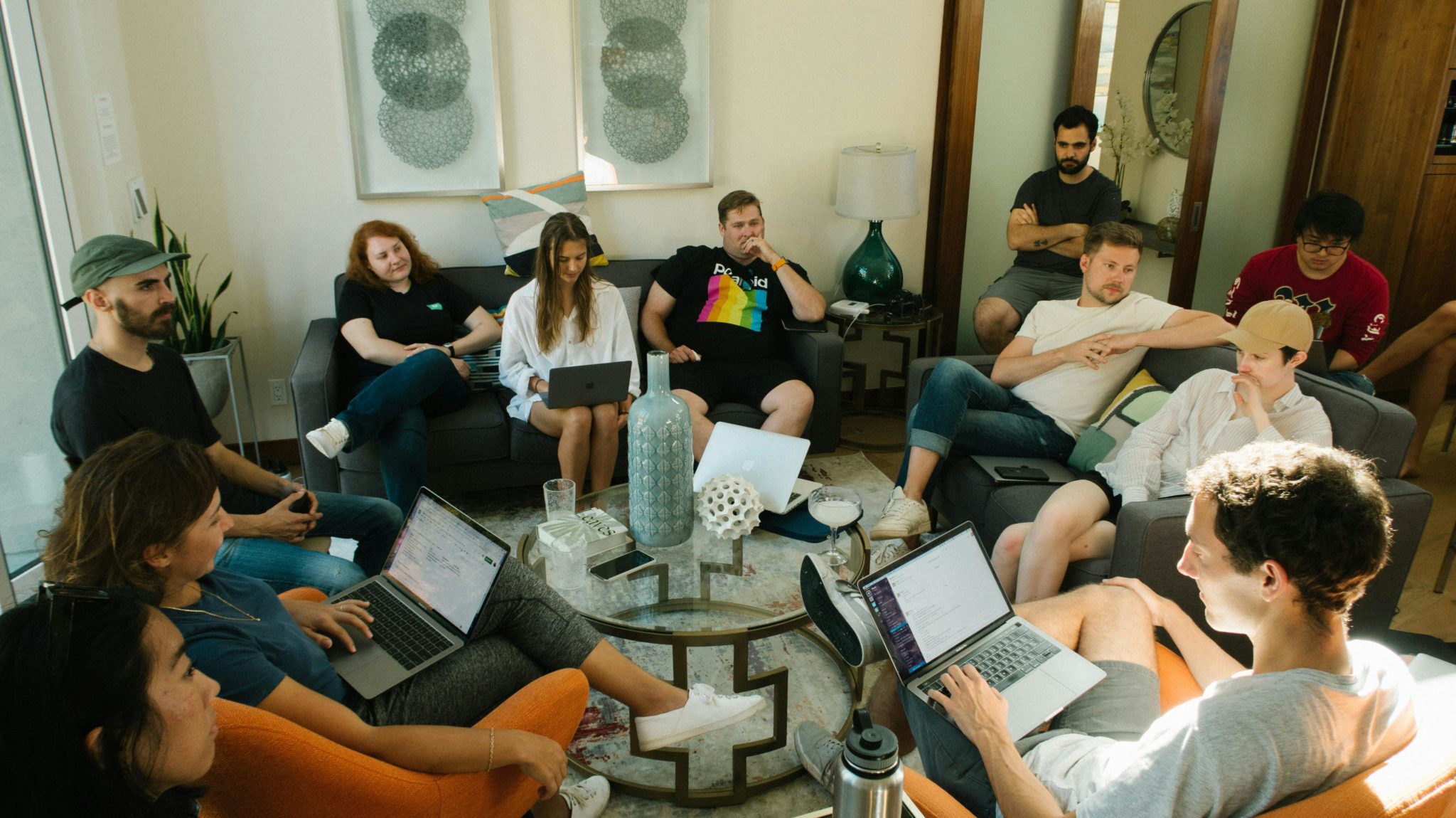 Junge Menschen sitzen mit Laptops gemütlich in einem Kreis.