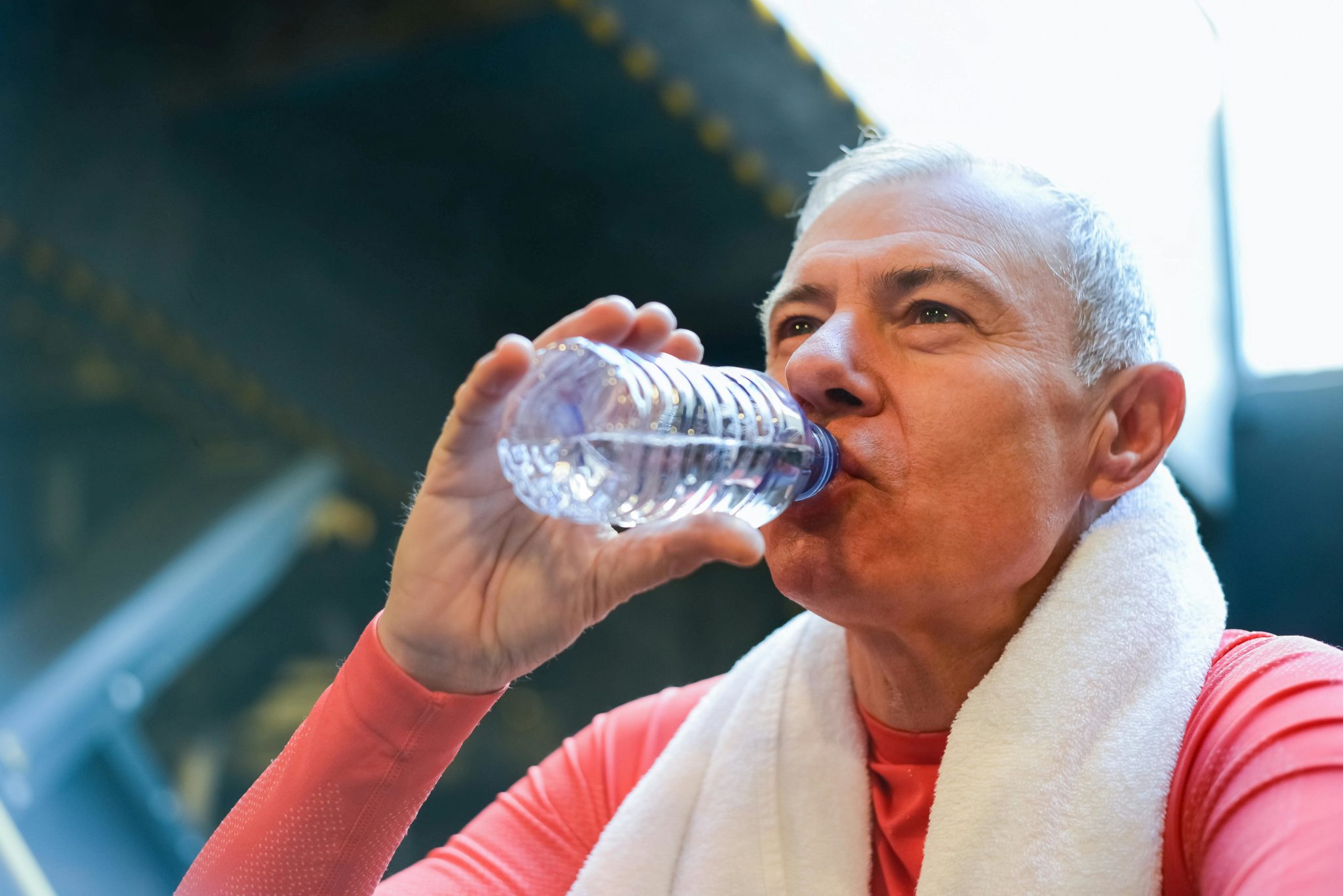 Älterer Sportler trinkt aus einer PET Flasche.