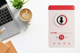 Man sieht einen Laptop, eine Kaffetasse und daneben ein Bild eines Podcast, der auf einem Handy spielt