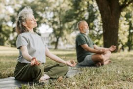 zwei ältere Menschen machen Yoga im Park