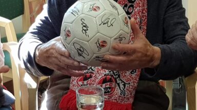 Zwei Hände halten einen signierten Fußball