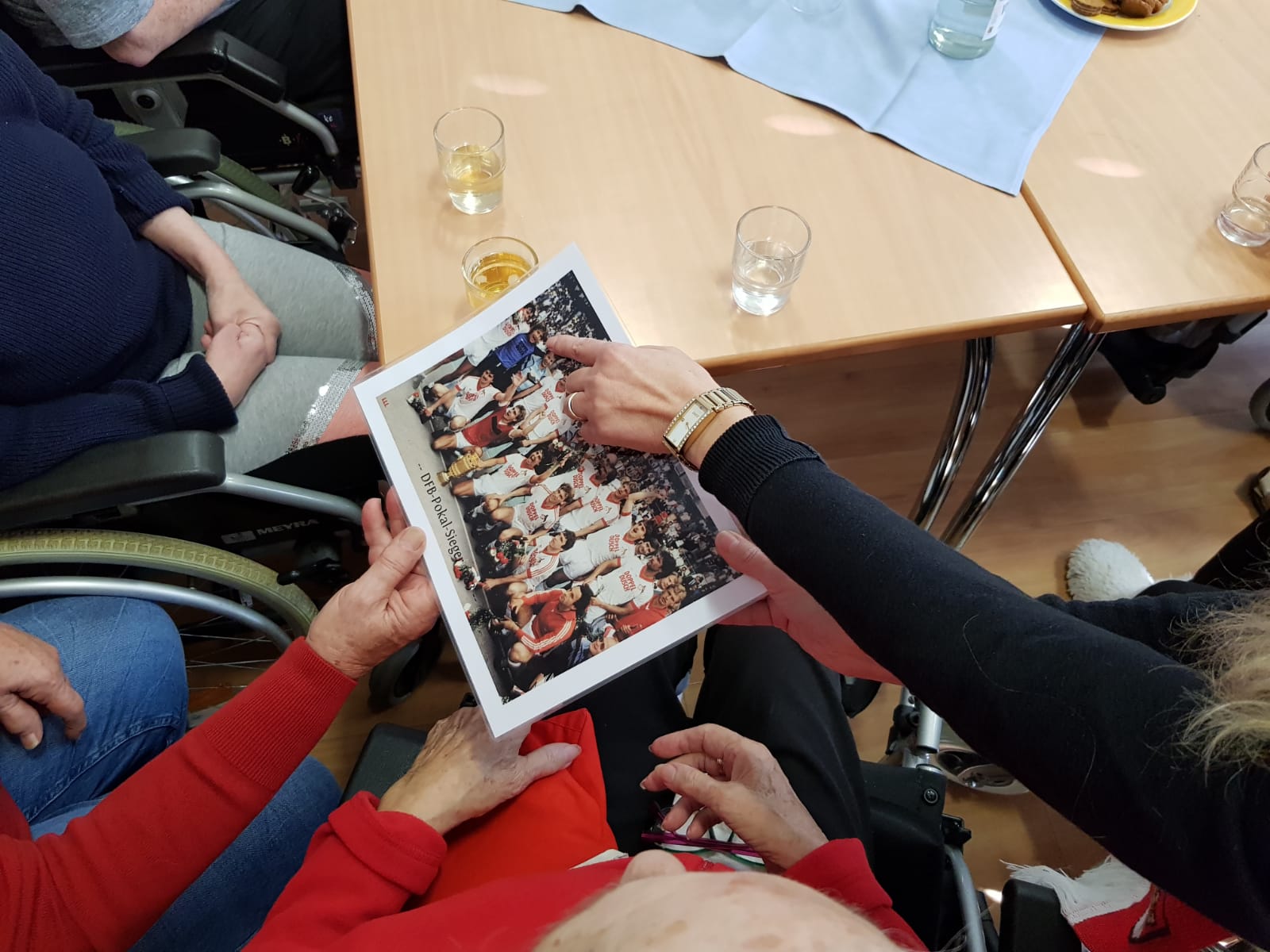 Mehrere Hände halten ein Gruppenfoto mit Spielern des FC