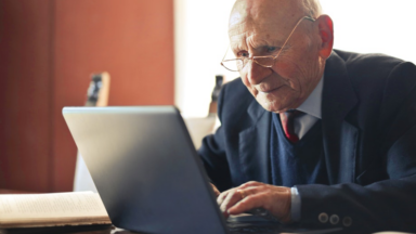 Ein Senior arbeitet an einem Laptop.