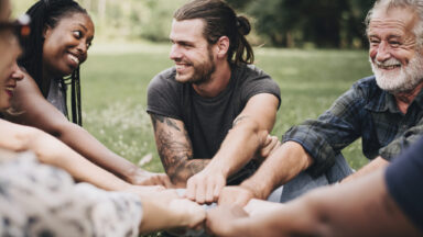Glückliche Menschen unterschiedlichen Alters stecken ihre Hände zusammen.