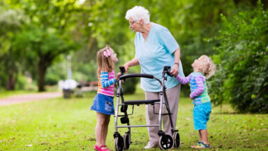Eine Senioren spielt mit zwei Kindern im Garten