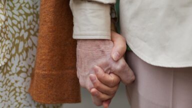 Zwei Senior*innen halten ihre Hände fest.