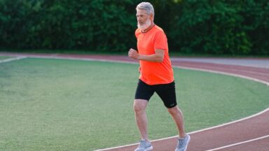 Ein Senior joggt auf einer Laufbahn.
