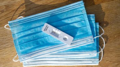 Ein Corona-Schnelltest liegt auf mehreren OP-Masken.