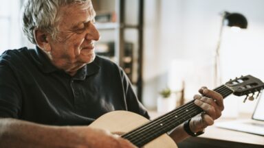Ein Senior spielt Gitarre.