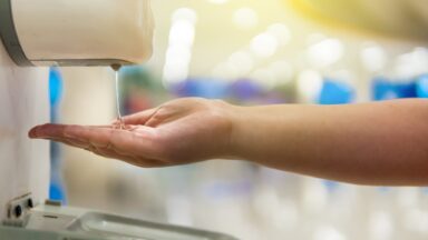 Hand unter einem elektrischen Desinfiktionsspender