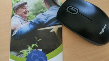 Eine Computermaus liegt neben dem Flyer des Regionalbüros Südwestfalen