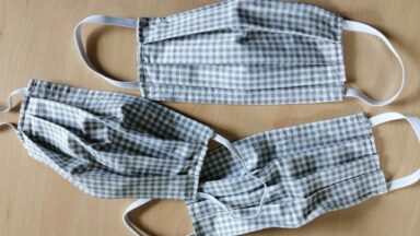 Als Symbol für Corona liegen 3 Mund-Nase-Bedeckungen auf einem Tisch.