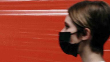 Eine Frau trägt einen schwarzen Mundschutz.