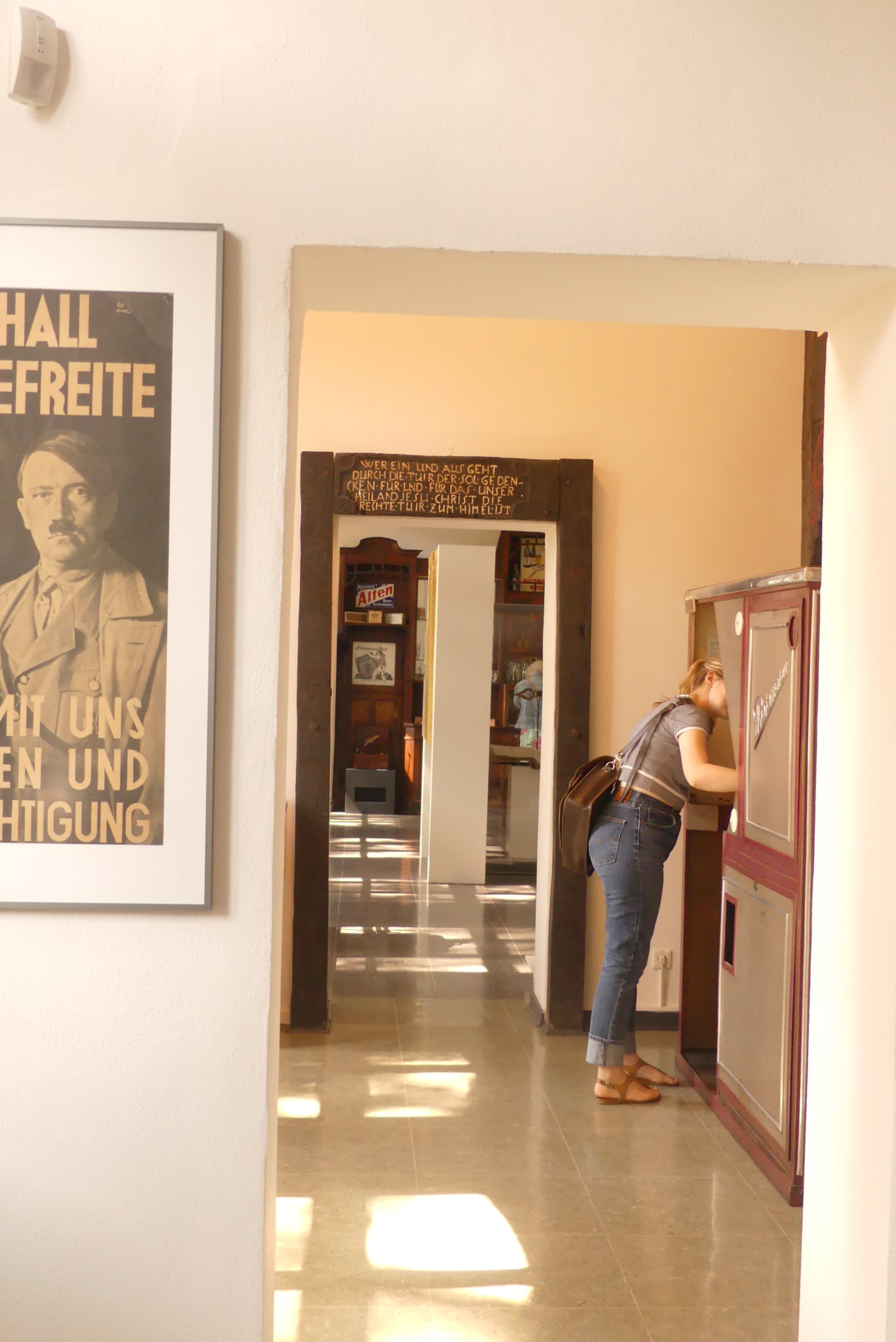 Eine Beschuerin blickt im Heimatmuseum hinter den Vorhang eines Ausstellungsstücks