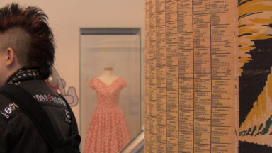 Aufnahme während der Museumsbesichtigung: Petticoat-Kleid im Hintergrund