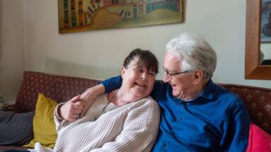 Ein Paar auf der Couch halten ihre Hände