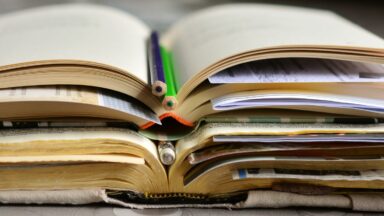 Gestapelte Bücher mit Stiften und Notizen darin