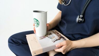 Pflegekraft stellt ihren Kaffee auf einem Buch ab.