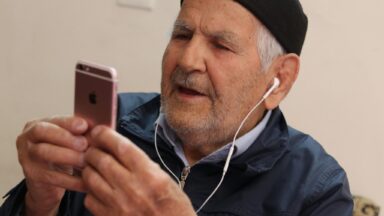 Eine ältere Person schaut auf sein Mobilfunkgerät.