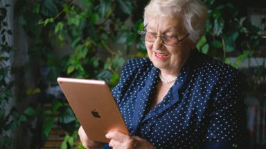Ältere Dame hält ein iPad und lächelt
