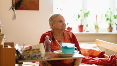 Alte Frau sitzt in ihrer Wohnung