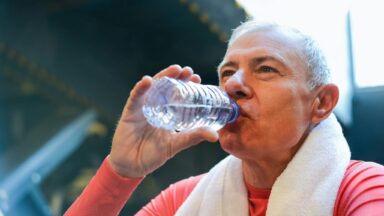 Älterer Sportler trinkt aus einer PET Flasche.