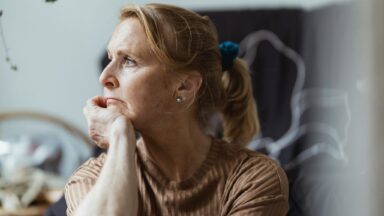 Frau schaut einsam aus dem Fenster