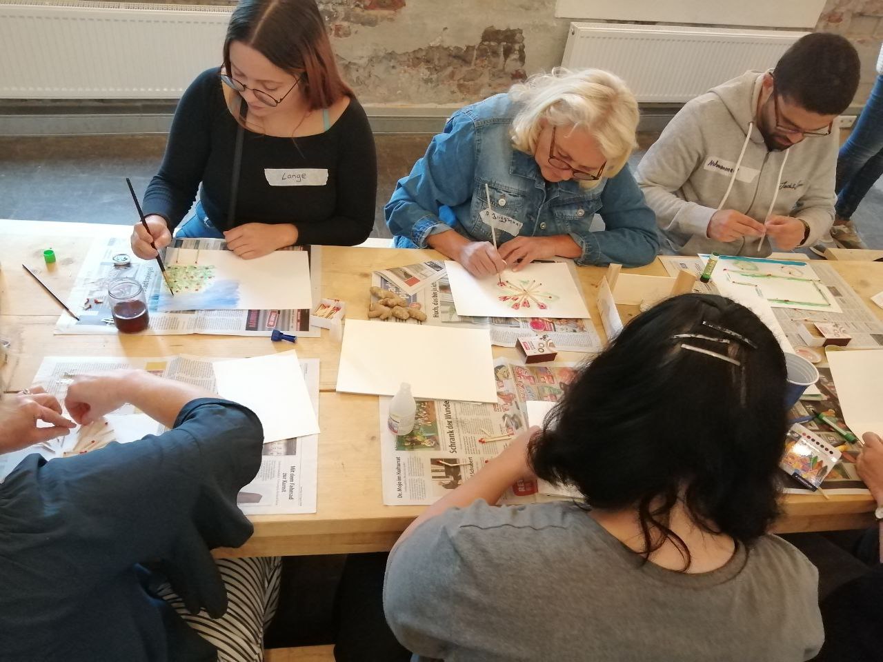 Teilnehmende arbeiten kreativ mit Pinsel, Farben etc.