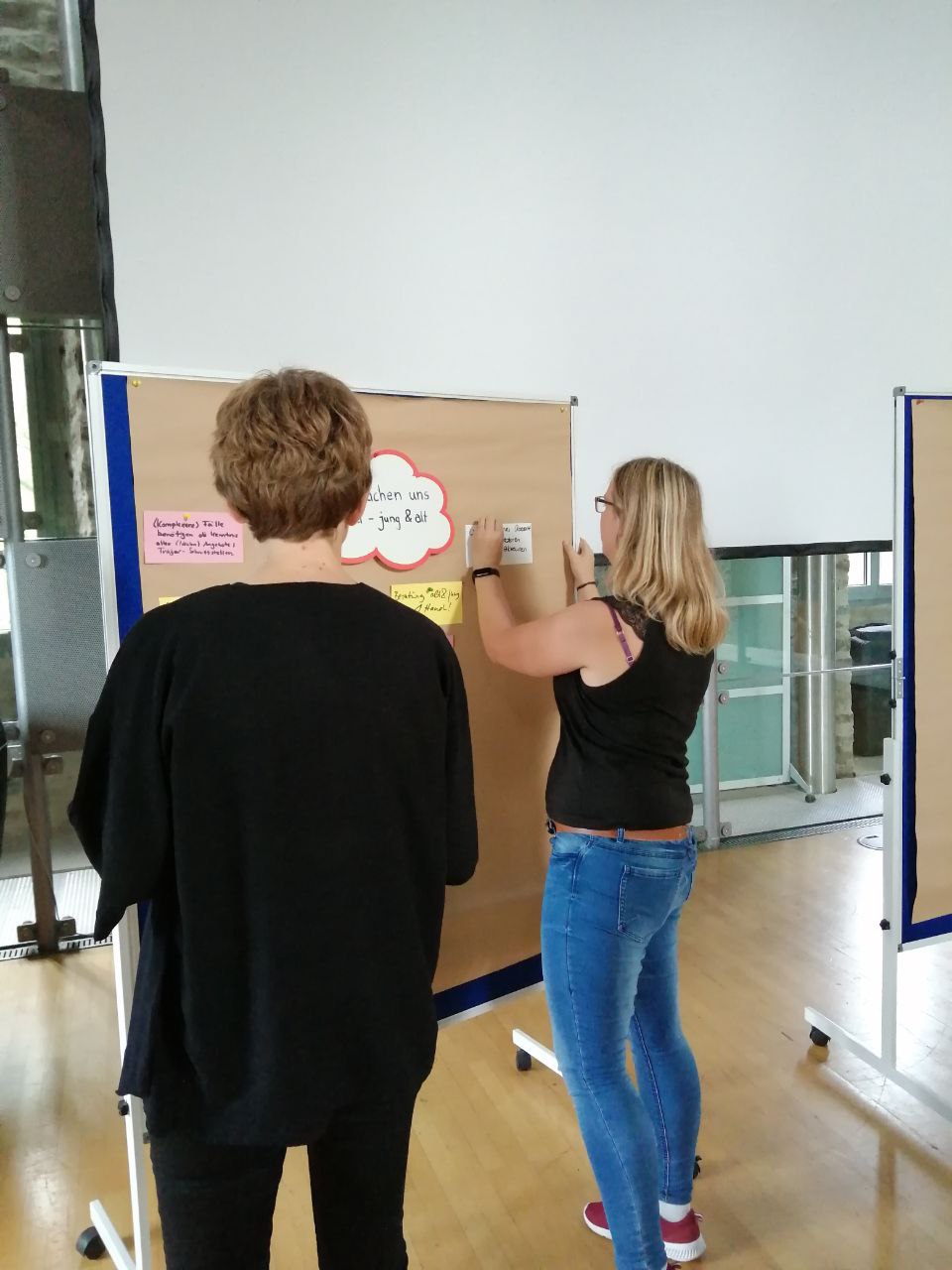 zwei Teilnehmerinnen heften karten an eine Metaplanwand