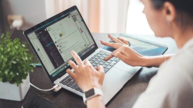 Man sieht eine Person etwas in eien Laptop tippen